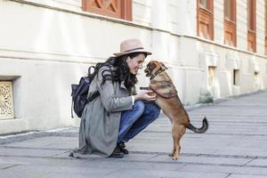 happy hipster woman playing with her dog on the street. stylish girl with funny dog resting, hugging and having fun, cute moments. photo