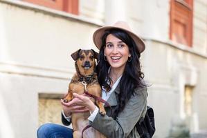 young attractive woman playing with her dog on the city street, lifestyle people concept. Beauty woman with her dog playing outdoors photo