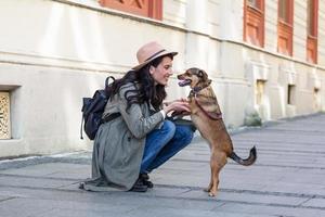 happy hipster woman playing with her dog on the street. stylish girl with funny dog resting, hugging and having fun, cute moments. space for text photo