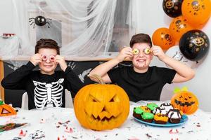 Happy Halloween  Attractive young boy with his big brother are preparing for Halloween party. Brothers in costumes are having fun and playing with scary eyes decoration photo