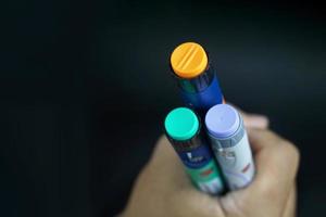 hombre asiático con piel marrón oscura sosteniendo una pluma de insulina. el equipo médico es fácil de autoinyectarse foto