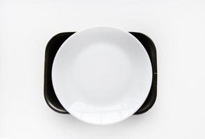 White porcelain plate on a black backing on a white background. Dishes on black material. A white plate. photo