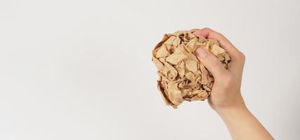 The man's hand is holding crumpled brown paper on white background. photo