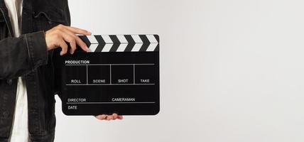 parte del cuerpo de un hombre sostiene una claqueta negra o una pizarra de película sobre fondo blanco. estudio de tiro foto