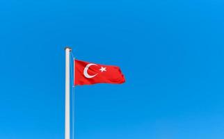 Turkish flag on a flagpole against a clear blue sky with copy space. Idea for background or wallpaper photo