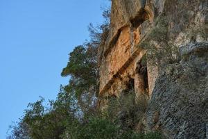 fethiye, turquía - 13 de noviembre de 2022. tumbas de roca griegas en la ladera de una montaña en la antigua telmessos en lycia, turquía foto