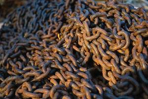 Rusty anchor chain is dumped on the pier, close-up selective focus. Heap of old heavy rusty chain links idea for background photo