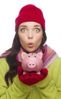 Expressive Mixed Race Woman Wearing Winter Hat Holding Piggybank photo