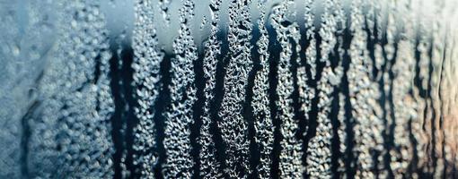 Texture of misted glass in winter. Frozen drops of water in sun on window. photo