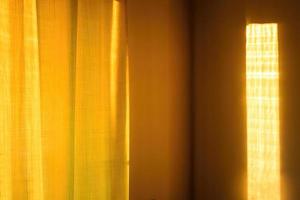 Sunbeam on yellow wall of house. Surface texture with sun glare. photo