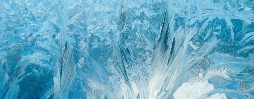 Frosty patterns on glass. Christmas background. Ice on winter window. Abstract crystals close up. photo