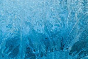 Frosty patterns on glass. Christmas background. Blue ice on winter window. photo