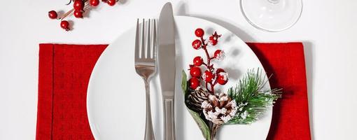 Christmas table setting. Plate and cutlery on red napkin. Decoration for festive dinner. photo