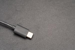 Close up of USB Type C connector with a grey cable on a dark background. Side close-up photo of grey type-c cable.