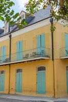 New Orleans, Louisiana, USA. November 4, 2022. A bright yellow stone building with closed blue shutters. photo