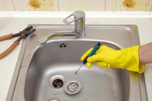 Close-up of handsome plumber hands repairing drain of kitchen sink photo