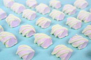 Colorful marshmallow laid out on blue paper background. pastel creative textured pattern. Perspective macro shot photo