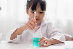 education, science, chemistry and children concept - kids or students with test tube making experiment at school laboratory photo