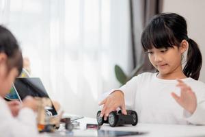 Asia students learn at home in coding robot cars and electronic board cables in STEM, STEAM, mathematics engineering science technology computer code in robotics for kids concept. photo