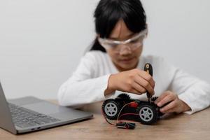 Asia students learn at home in coding robot cars and electronic board cables in STEM, STEAM, mathematics engineering science technology computer code in robotics for kids concept. photo