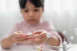 Asian Little girl studies the solar system in geography class. looking at the scale model of planets photo