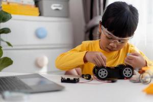 Asia students learn at home in coding robot cars and electronic board cables in STEM, STEAM, mathematics engineering science technology computer code in robotics for kids concept. photo