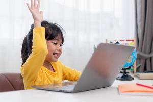 First day at school. Asian little girl using a laptop computer, studying through online e-learning system. photo