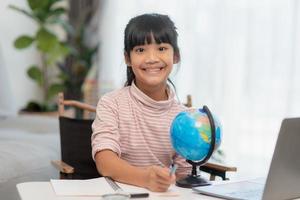 Asian little girl is learning the globe model, concept of save the world and learn through play activity for kid education at home. photo