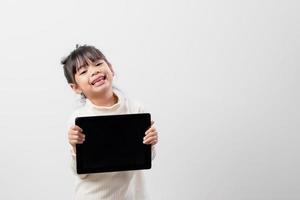 Asian little girl holding and using the digital tablet on white studio background, free copy space photo