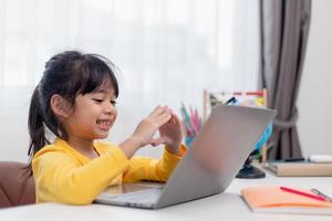 First day at school. Asian little girl using a laptop computer, studying through online e-learning system. photo