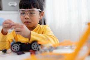 Asia students learn at home in coding robot cars and electronic board cables in STEM, STEAM, mathematics engineering science technology computer code in robotics for kids concept. photo