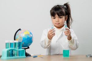 education, science, chemistry and children concept - kids or students with test tube making experiment at school laboratory photo