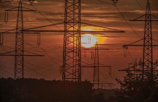 postes de energía frente al sol que se hunde foto