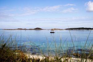 velero en el mar, junto a la playa en las islas scilly foto