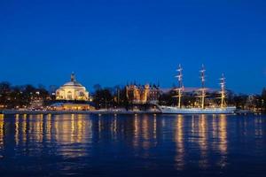 una vista nocturna del puerto de estocolmo, con un barco foto