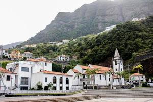 Town buildings and a church in Sao Vicente, with mountains in the background photo