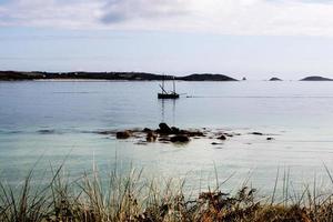 velero en el mar, junto a la playa en las islas scilly foto