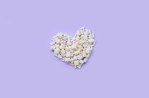 Colorful marshmallow laid out on violet and pink paper background. pastel creative textured heart. minimal photo