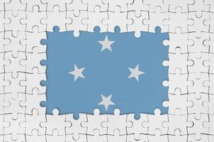 Micronesia flag in frame of white puzzle pieces with missing central part photo