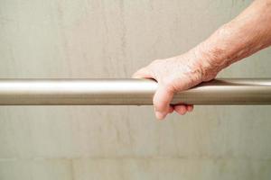 Asian elderly old woman patient use toilet support rail in bathroom, handrail safety grab bar, security in nursing hospital. photo