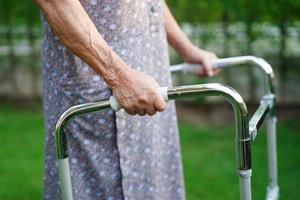 Asian elderly woman disability patient walk with walker in nursing hospital, medical concept. photo