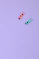 Two colored wooden pegs lie on texture background of fashion pastel violet color paper in minimal concept photo