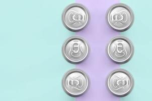 muchas latas de cerveza metálicas sobre fondo de textura de papel de colores violeta pastel y azul de moda en concepto mínimo foto