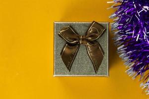 small gift box with ribbons top view on yellow background, One brown gift box for christmas and New Year 2023 occasion concept banner design.