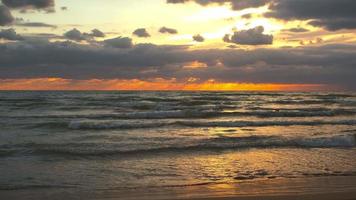 bela vista do pôr do sol no mar, o sol brilha na câmera, as ondas quebram na praia. vídeo ao vivo 4k video