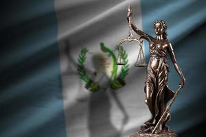 Guatemala flag with statue of lady justice and judicial scales in dark room. Concept of judgement and punishment photo