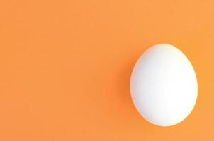 One white easter egg on a bright orange background photo