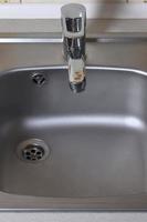 Empty clean silvery kitchen sink and water faucet close up photo