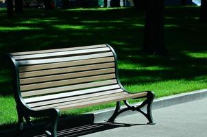 Empty wooden bench in the summer park against the green grass photo