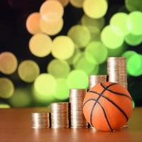 baloncesto y montones de monedas de oro en el gráfico de crecimiento en el fondo borroso del bokeh foto